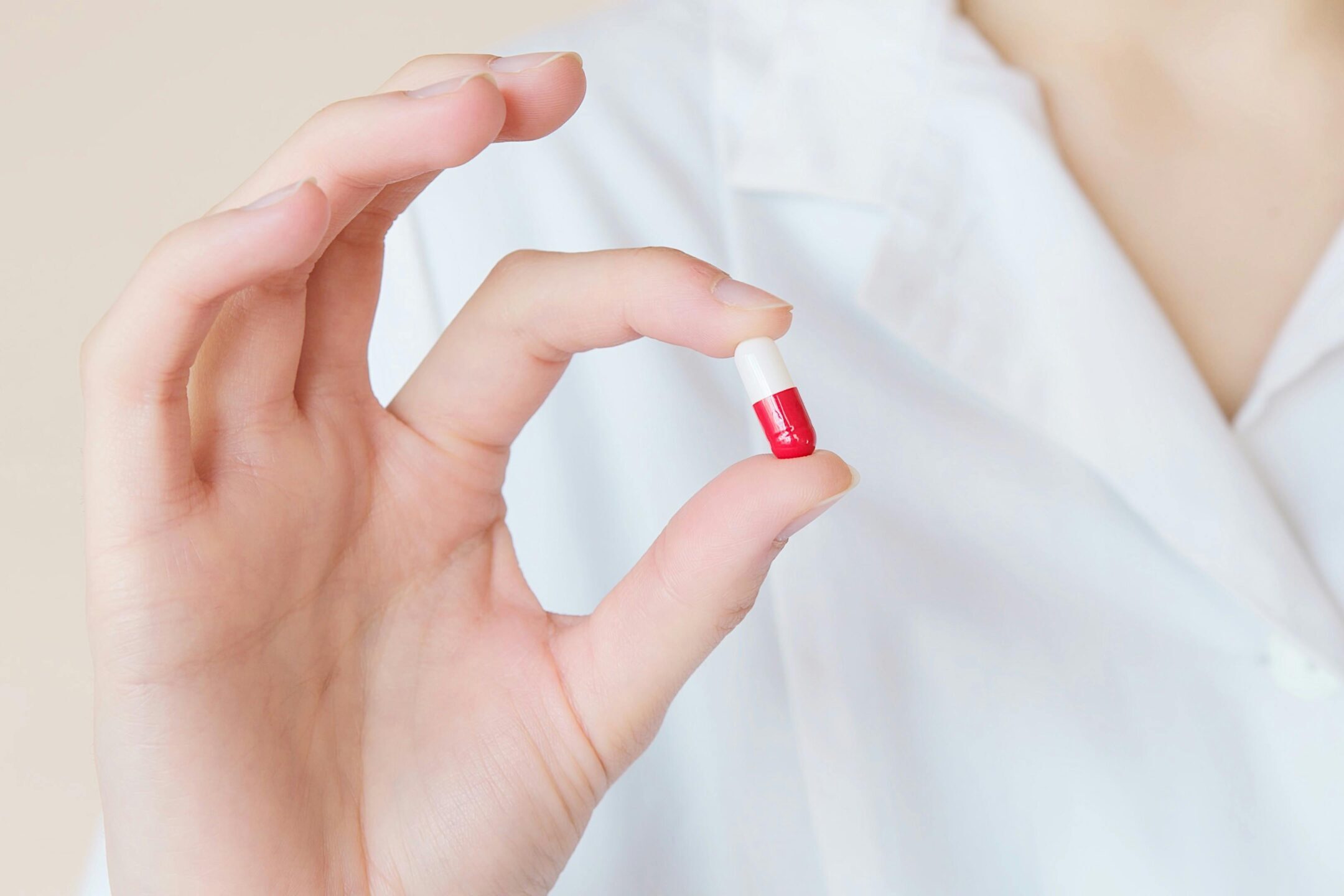 A healthcare professional holds a red and white capsule, exemplifying modern medicine.