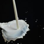 Capturing a dynamic splash of milk on a spoon in mid-air with dark background.