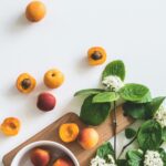 A flat lay of fresh apricots and blossoms on a board showcasing summer freshness.