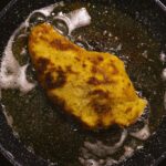Golden schnitzel frying in a pan, capturing the essence of home-cooked comfort food.